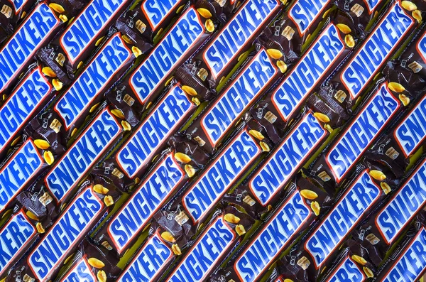Muitas barras de chocolate Snickers empilhadas de perto. Barras Snickers são produzidas pela Mars Incorporated. Snickers foi criado por Franklin Clarence Mars em 1930 — Fotografia de Stock