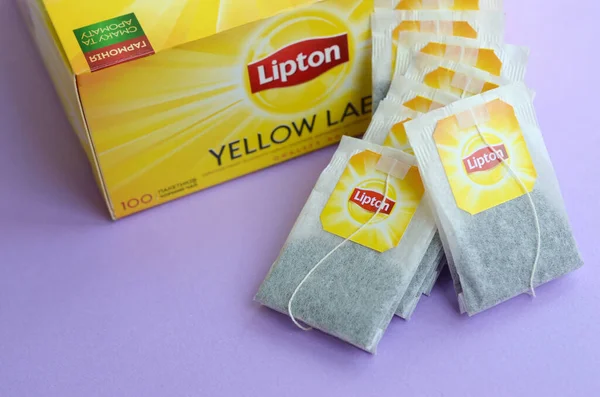 Lipton Yellow Label μαύρο πακέτο τσαγιού και φακελάκια τσαγιού σε παστέλ λιλά επιφάνεια κοντά. Lipton είναι μια παγκοσμίως γνωστή μάρκα τσαγιού — Φωτογραφία Αρχείου