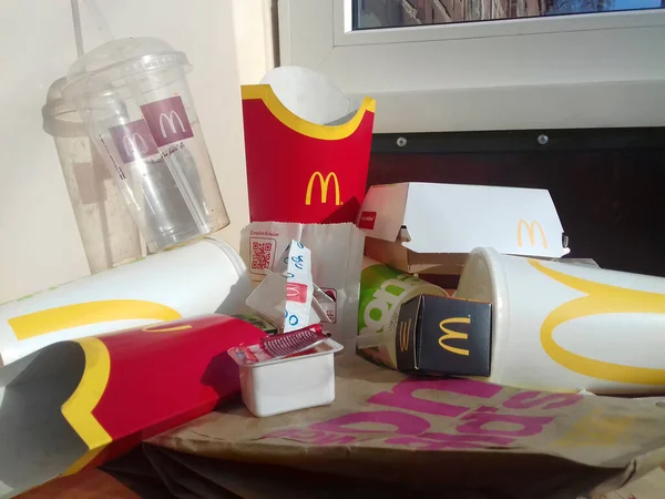 Used paper wrappings and disposable packs with McDonalds design and logo in pile on table. McDonalds recycle trash after usage — Stock Photo, Image