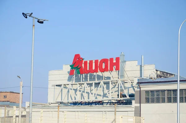 KHARKOV, UCRANIA - 20 DE OCTUBRE DE 2019: Logotipo del supermercado Auchan en la azotea del edificio. Auchan es un grupo minorista internacional francés — Foto de Stock