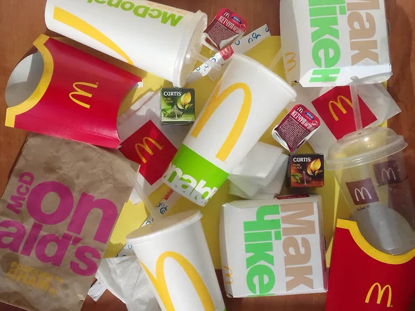 Embalagens de papel usadas e embalagens descartáveis com design e logotipo McDonalds em pilha na mesa. McDonalds reciclar lixo após o uso — Fotografia de Stock