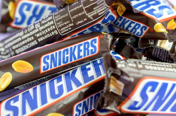 Mnoho čokoládových tyčinek Snickers naskládaných zblízka. Tyčinky Snickers vyrábí společnost Mars Incorporated. Snickers vytvořil Franklin Clarence Mars v roce 1930 — Stock fotografie