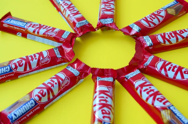 Kit Kat barras de chocolate en rojo envoltura se encuentra en el fondo amarillo. Kit kat creado por Rowntree 's de York en Reino Unido y ahora es producido globalmente por Nestle —  Fotos de Stock