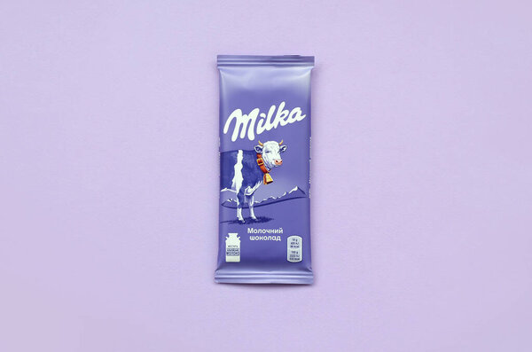 Milka chocolate tablet in classic violet wrapping on lilac background. Milka is brand of chocolate confection originated in Switzerland in 1901