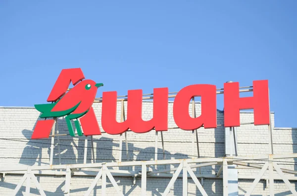 KHARKOV, UCRANIA - 20 DE OCTUBRE DE 2019: Logotipo del supermercado Auchan en la azotea del edificio. Auchan es un grupo minorista internacional francés — Foto de Stock