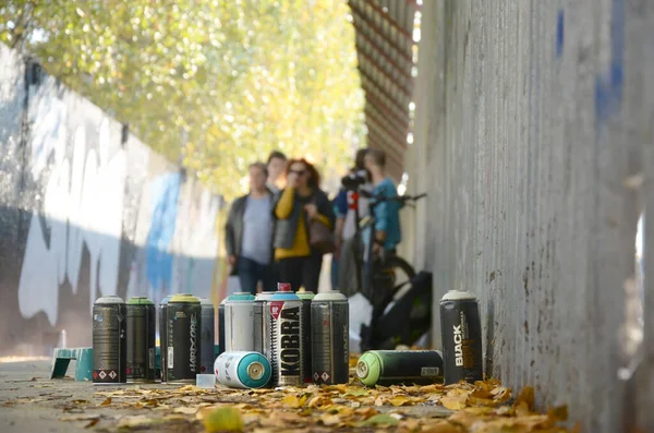 KHARKOV, UKRAINE - OCTOBER 19, 2019: Used spray cans for graffiti painting by many paint brands outdoors in autumn leafs and artist in painting process — Stock Photo, Image