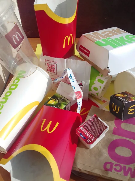 Embalajes de papel usados y paquetes desechables con diseño y logotipo de McDonalds en una pila sobre la mesa. McDonalds recicla basura después del uso —  Fotos de Stock