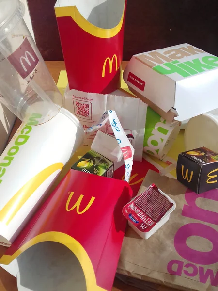 Použité papírové obaly a jednorázové obaly s designem a logem McDonalds na stole. McDonalds po použití recyklovat koš — Stock fotografie