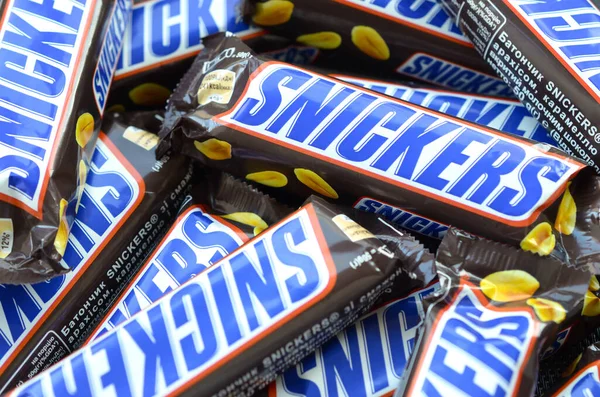 Muchas barras de chocolate Snickers apiladas de cerca. Las barras Snickers son producidas por Mars Incorporated. Snickers fue creado por Franklin Clarence Mars en 1930 — Foto de Stock