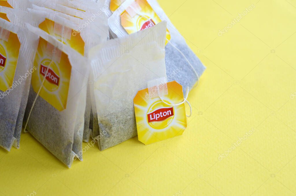 KHARKOV, UKRAINE - OCTOBER 4, 2019: Lipton Yellow Label black tea bags on pastel yellow surface close up. Lipton is a world famous brand of tea
