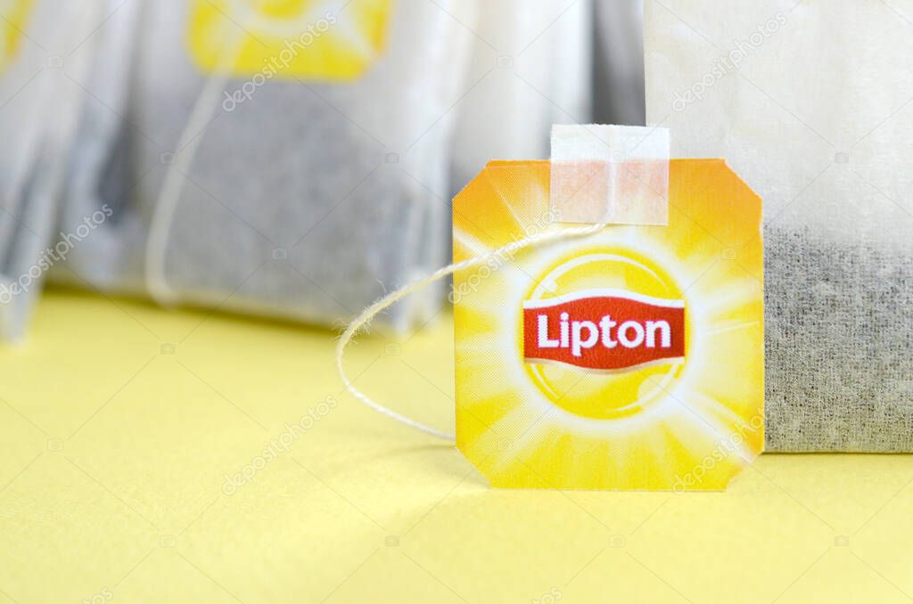 KHARKOV, UKRAINE - OCTOBER 4, 2019: Lipton Yellow Label black tea bags on pastel yellow surface close up. Lipton is a world famous brand of tea