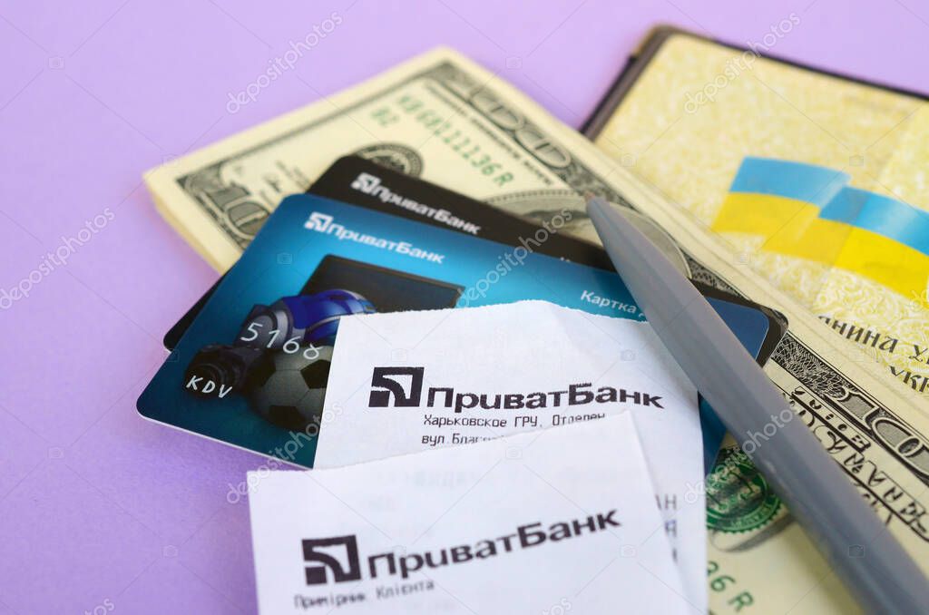 KHARKOV, UKRAINE - OCTOBER 3, 2019: Privatbank check lies with credit cards and pen on dollar bills with passport. Privatbank is a main financial department in Ukraine, depository of money in hryvnia