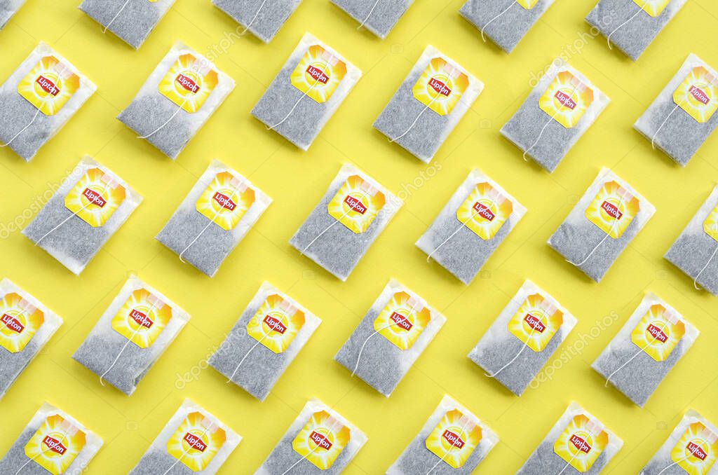 KHARKOV, UKRAINE - OCTOBER 4, 2019: Flat lay of Lipton Yellow Label black tea bags on pastel yellow surface. Lipton is a world famous brand of tea