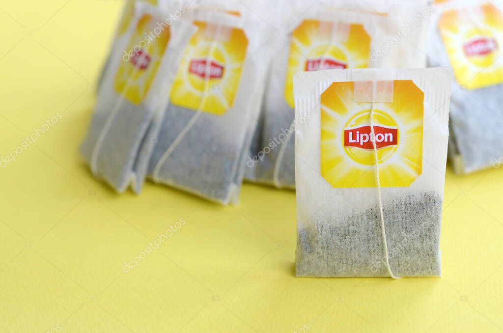 KHARKOV, UKRAINE - OCTOBER 4, 2019: Lipton Yellow Label black tea bags on pastel yellow surface close up. Lipton is a world famous brand of tea
