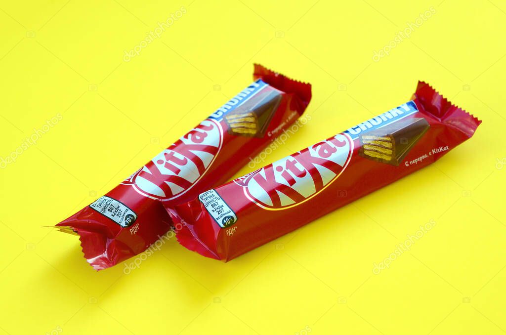 Kit Kat barras de chocolate en rojo envoltura se encuentra sobre fondo amarillo brillante. Kit
