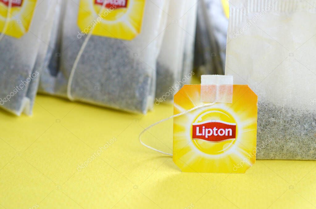 KHARKOV, UKRAINE - OCTOBER 4, 2019: Lipton Yellow Label black tea bags on pastel yellow surface close up. Lipton is a world famous brand of tea
