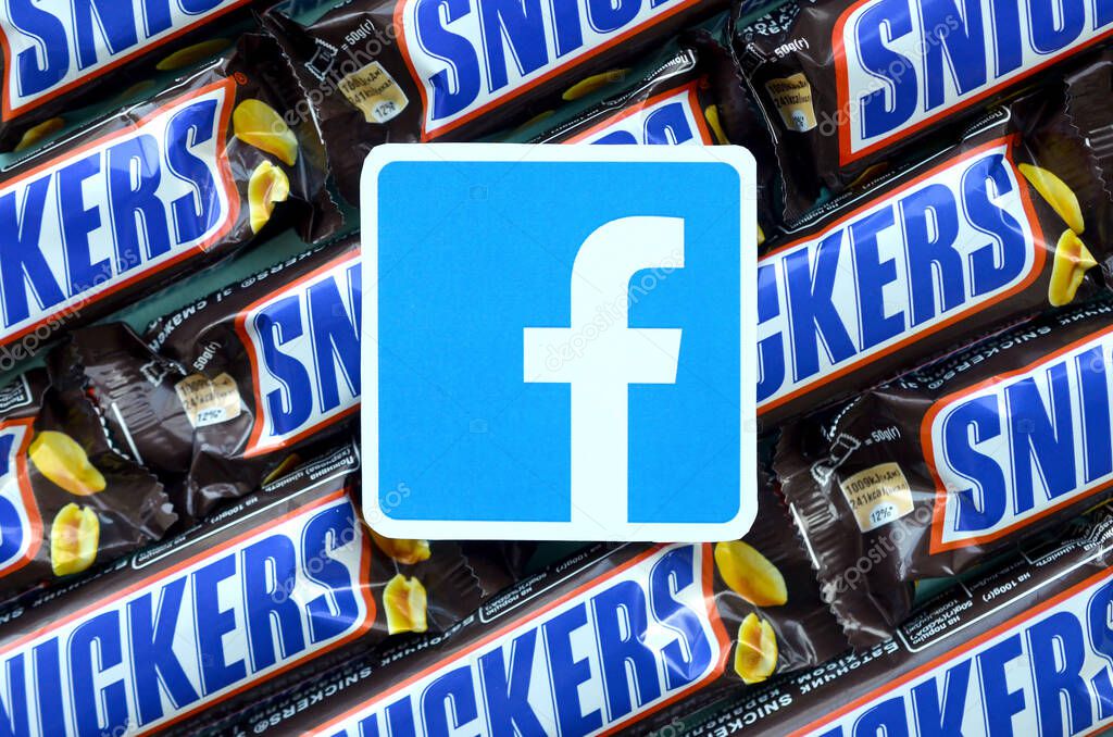 KHARKOV, UKRAINE - OCTOBER 2, 2019: Facebook paper logo on many Snickers chocolate covered wafer bars in brown wrapping. Advertising chocolate product in Facebook social network and world wide web