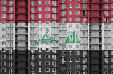 Yapım aşamasındaki çok katlı konut binasının üzerine boyanmış Irak bayrağı. Büyük tuğla duvar zemininde desenli pankart