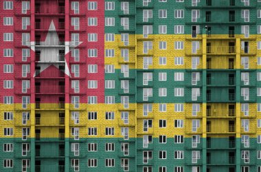 Togo bayrağı yapım aşamasındaki çok katlı konut binasının boya renkleriyle resmedilmiş. Büyük tuğla duvar zemininde desenli pankart