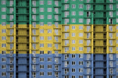 Gabon bayrağı, yapım aşamasındaki çok katlı yerleşim yerinin boyalarıyla resmedilmiş. Büyük tuğla duvar zemininde desenli pankart