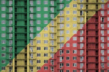 Kongo bayrağı yapım aşamasındaki çok katlı konut binasının boya renkleriyle resmedilmiş. Büyük tuğla duvar zemininde desenli pankart