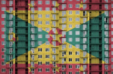 Yapım aşamasındaki çok katlı yerleşim yerlerinin üzerine boyanmış Grenada bayrağı. Büyük tuğla duvar zemininde desenli pankart