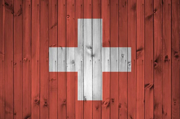 古い木製の壁に明るい塗料の色で描かれたスイスの旗が閉じます ざらざらとした背景に書かれた旗 — ストック写真