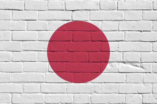 Japan flag depicted in paint colors on old brick wall close up. Textured banner on big brick wall masonry background