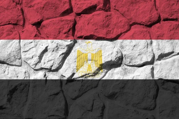 Egypt flag depicted in paint colors on old stone wall close up. Textured banner on rock wall background