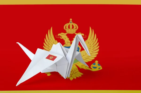 Montenegro flag depicted on paper origami crane wing. Oriental handmade arts concept