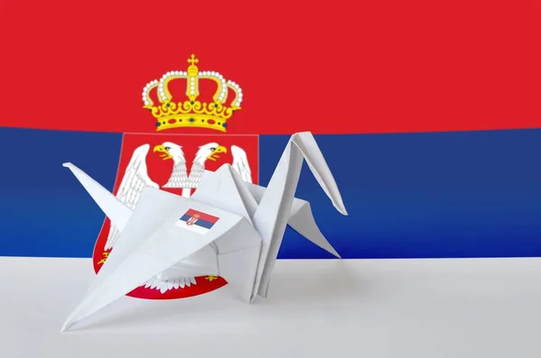 Serbia flag depicted on paper origami crane wing. Oriental handmade arts concept