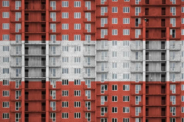 Austria flag depicted in paint colors on multi-storey residental building under construction. Textured banner on big brick wall background