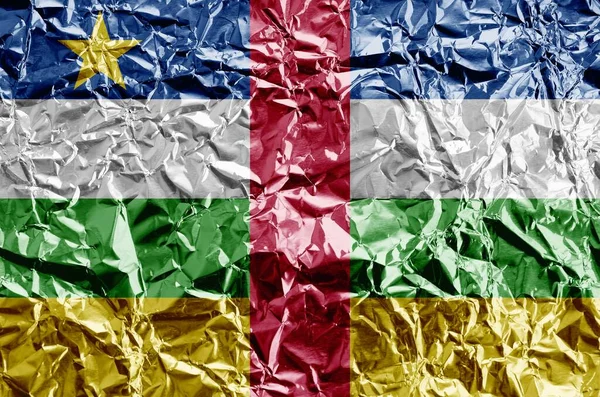 Central African Republic flag depicted in paint colors on shiny crumpled aluminium foil close up. Textured banner on rough background