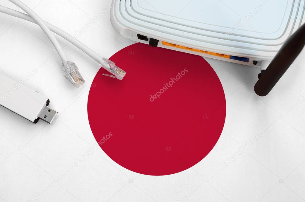 Japan flag depicted on table with internet rj45 cable, wireless usb wi-fi adapter and router. Internet connection concept