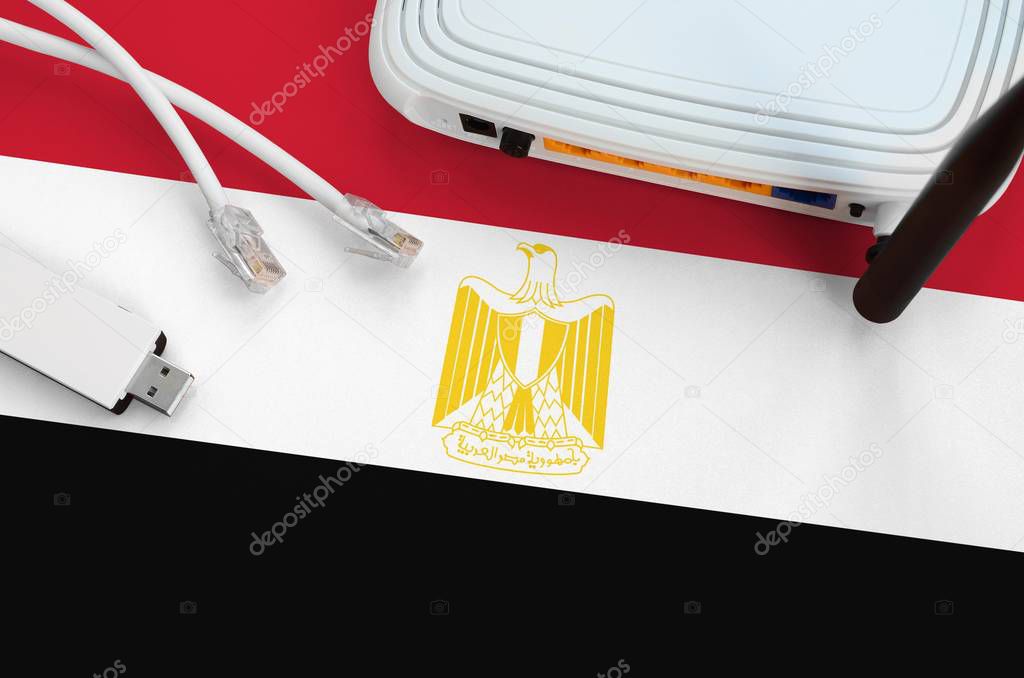 Egypt flag depicted on table with internet rj45 cable, wireless usb wi-fi adapter and router. Internet connection concept