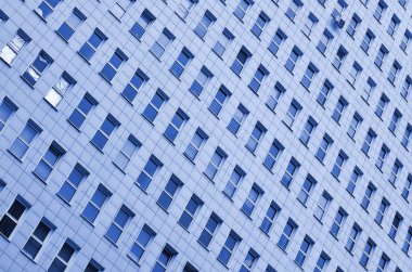 Çok katlı bir ofis binasının birçok penceresinin deseni. Modern çok katlı bir binanın duvarında çok sayıda plastik pencere var. hayalet klasik mavi renk