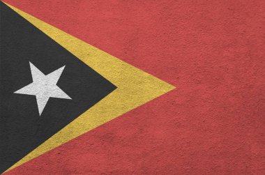Timor Leste bayrağı, eski kabartma duvarın üzerine parlak boya renkleriyle resmedilmiş. Kabataslak arkaplanda desenli pankart