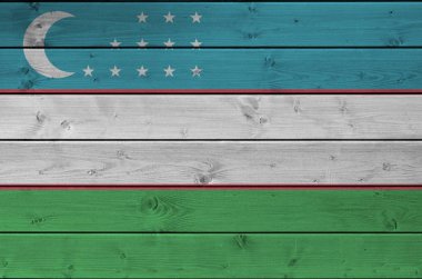 Özbekistan bayrağı, eski ahşap duvarda parlak boya renkleriyle resmedilmiş. Kabataslak arkaplanda desenli pankart