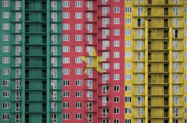 Yapım aşamasında olan çok katlı yerleşim yerinin boyalı renkleriyle betimlenmiş fotoğraf makinesi bayrağı. Büyük tuğla duvar zemininde desenli pankart