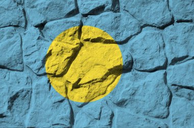 Eski taş duvarlara boyanmış Palau bayrağı. Kapatın. Kayalık duvar arkaplanındaki desenli pankart