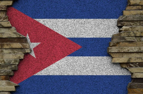 Cuba flag depicted in paint colors on old stone wall close up. Textured banner on rock wall background