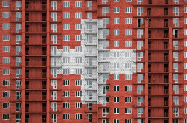 瑞士国旗在建造中的多层住宅楼上涂上了彩绘 大砖墙背景上的纹理横幅 — 图库照片