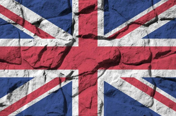 Great britain flag depicted in paint colors on old stone wall close up. Textured banner on rock wall background