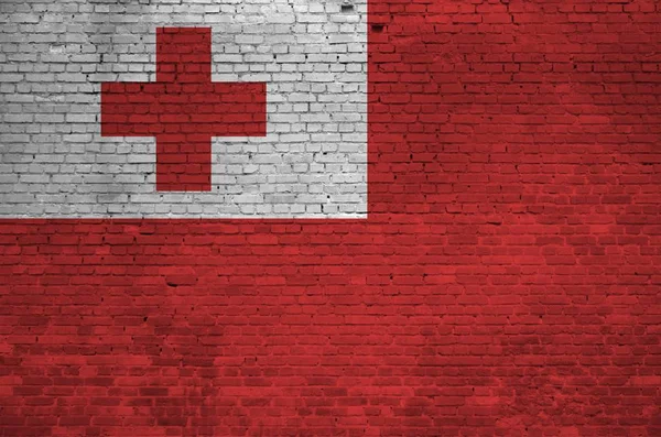 Tonga flag depicted in paint colors on old brick wall close up. Textured banner on big brick wall masonry background