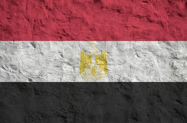 Egypt flag depicted in bright paint colors on old relief plastering wall close up. Textured banner on rough background