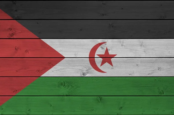 Western Sahara flag depicted in bright paint colors on old wooden wall close up. Textured banner on rough background