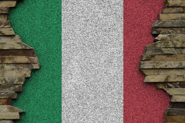 Italy flag depicted in paint colors on old stone wall close up. Textured banner on rock wall background