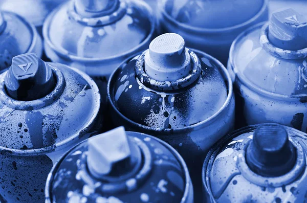 A lot of used spray cans of paint close-up. Dirty and smeared cans for drawing graffiti. The concept of a sweeping and careless drawing of paint. phantom classic blue color.