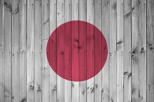 Japan flag depicted in bright paint colors on old wooden wall close up. Textured banner on rough background
