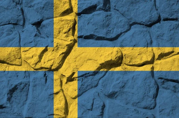 Sweden flag depicted in paint colors on old stone wall close up. Textured banner on rock wall background